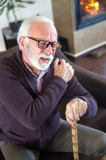 senior mann in schmerzen halten schulter - arthritis senior adult rheumatoid arthritis sadness stock-fotos und bilder