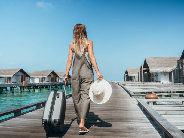 Woman pulls trolley on wooden pier in tropical destination