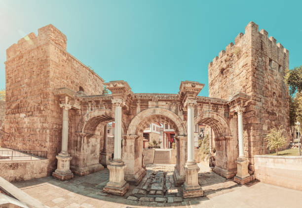 известным туристическим и археологическим памятником анталии является ворота императора адриана в старом городе. туристические направле� - ancient column past arch стоковые фото и изображения