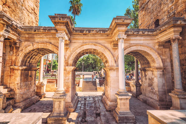 известным туристическим и археологическим памятником анталии является ворота императора адриана в старом городе. туристические направле� - ancient column past arch стоковые фото и изображения