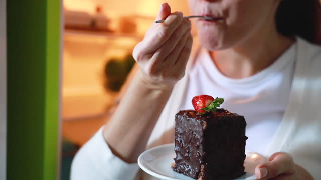 Young woman eat appetizing cake using fork feeling pleasant