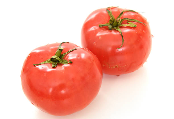 Ripe pink tomatoes with water drops on light background