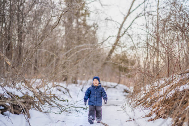 Young Asian boy enjoying some time outside playing in the snow during winter.