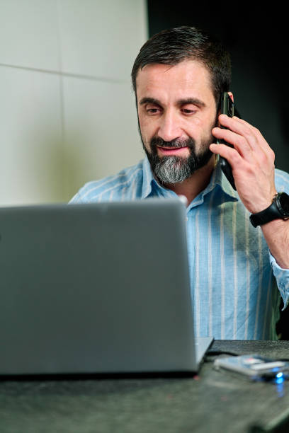 istock white man talking on the phone while smiling looking at the laptop screen 1301256894