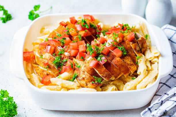 istock Cajun chicken pasta with cheese and tomato in white dish. 1301257037