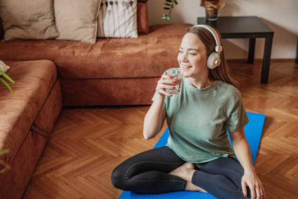 istock Young woman drinks water at home after home exercise 1301258179