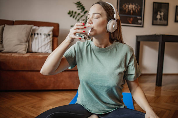istock Young woman drinks water at home after home exercise 1301258187
