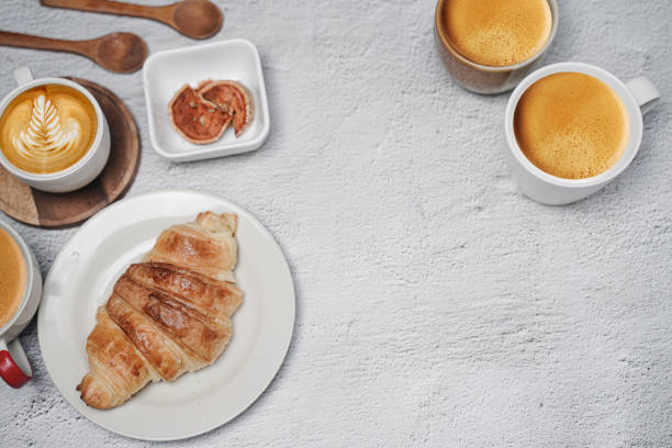 cup of coffee and Fresh baked croissant on white kitchen table. Top view with copyspace for your text.