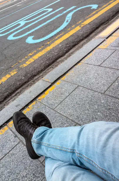 Photo of Feet of a man waiting a bus on a bus stop i