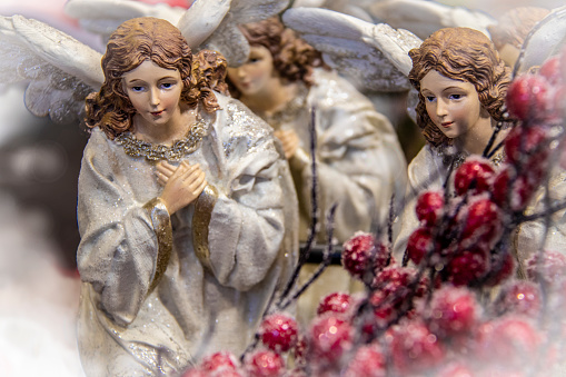 Heavenly angels at Christmas - Two praying beautiful angels with more blurred angels and holiday berries