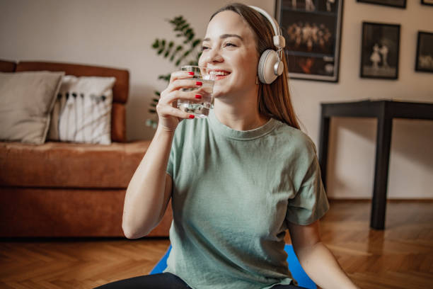 istock Young woman drinks water at home after home exercise 1301262615