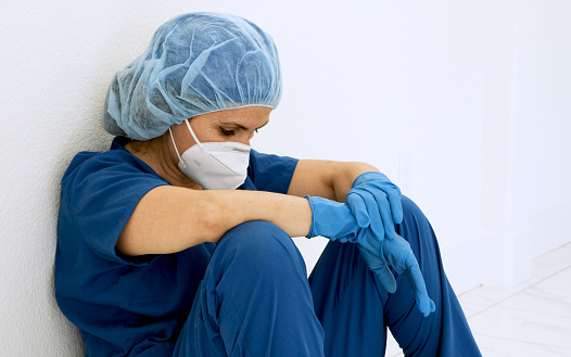 Trabajadora, triste, cansada, trabajadora sanitaria sentada en el suelo de un pasillo del hospital photo