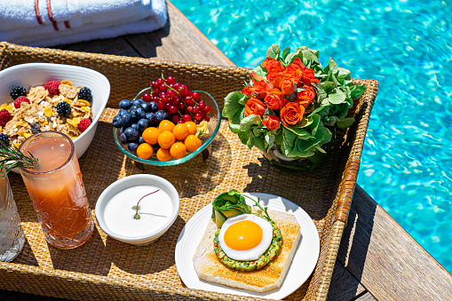 tray with assorted breakfast meal and drinks near swimming pool.
