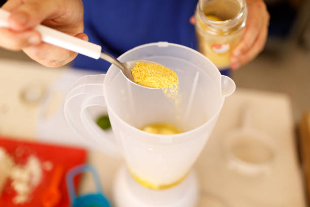 female hand holding a spoon adding nutritional yeast in the blender - yeast imagens e fotografias de stock