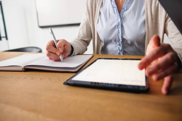istock Close Up Of A Woman Taking Notes And Using Digital Tablet In The Office 1301270048