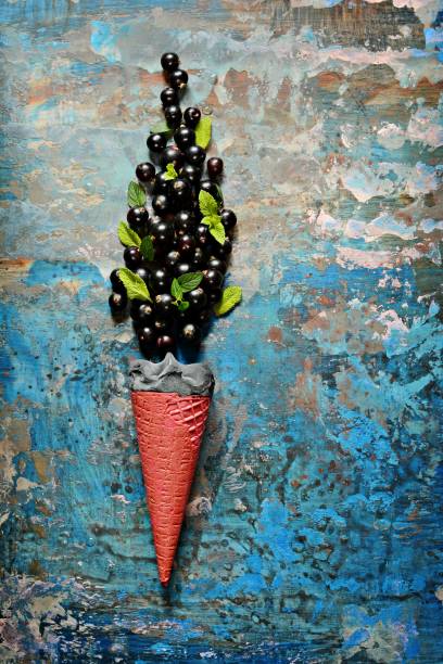 Ice cream in a waffle cup with black currant berries, and fresh mint leaves, copy space.Top view, flat lay. Fresh berries on a blue  background. Summer and healthy food concept.