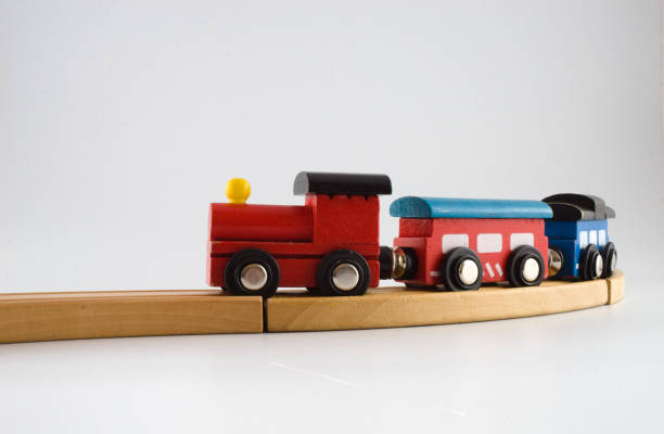 Colourful wooden toy train on train tracks, plain background
