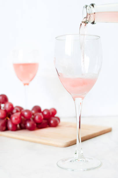 wino różane wlewa się do szklanki z butelki - champagne pink luxury table zdjęcia i obrazy z banku zdjęć