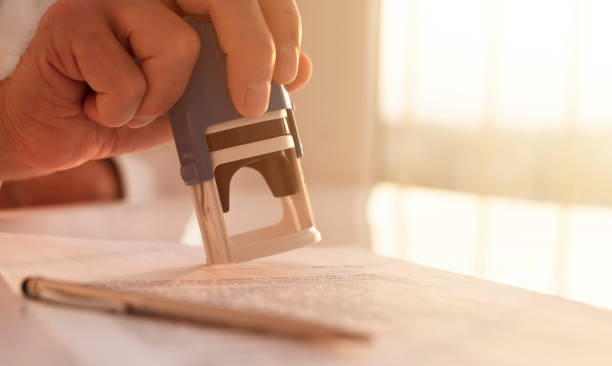 Stamping document close up, seal over contract in male hand Stamping document close up, seal over contract in male hand. notary stock pictures, royalty-free photos & images