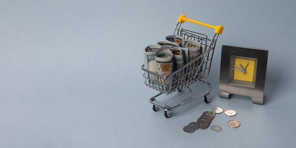 Cash in shopping cart with clocks. Time to buy, for sale. Banner with copy space