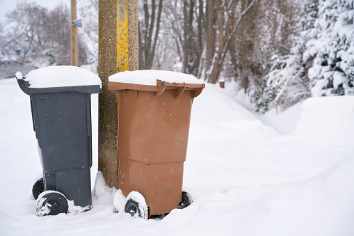 Garbage cans at the roadside on a snowed-in street in Magdeburg in Germany