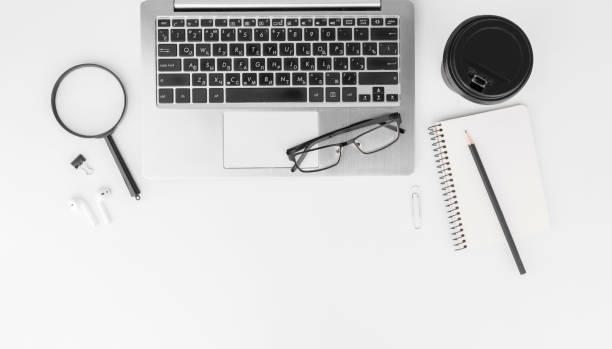 istock Workplace in the office with a white desk. Top view from above of keyboard with notebook,pencil,eyeglasses and coffee. Space for modern creative work of designer. Flat lay with copy space. Business and finance concept. 1301276552