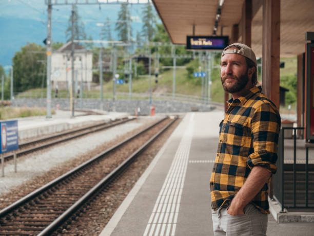 istock Man waits for train at station 1301276600