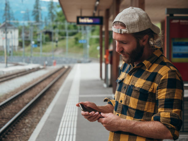 istock Man checks phone at train station 1301276617