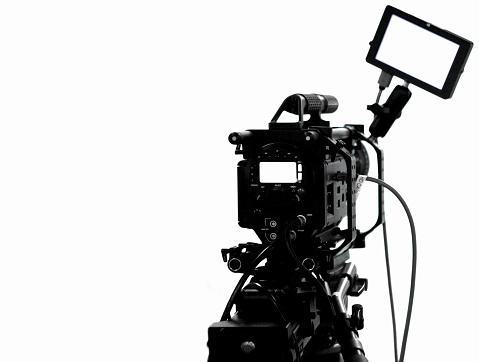 Camera on a tripod in front of a white background while filming a film production.