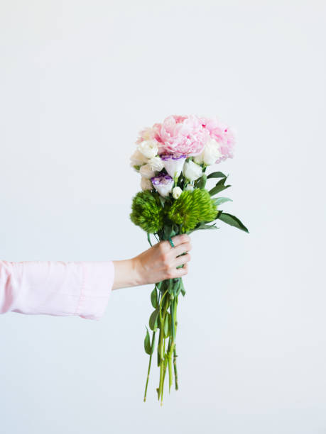 istock Female hand holding beautiful pastel peony bouquet 1301276944