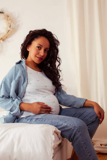 young pretty african american woman pregnant laying in bed, lifestyle people concept stock photo