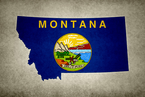 Grunge map of the state of Montana (USA) with its flag printed within its border on an old paper.