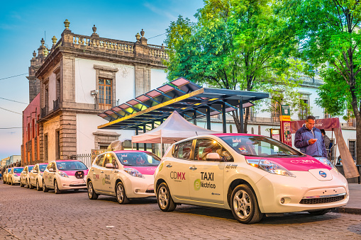 Electric taxis are being charged at a charging station in downtown Mexico City, Mexico in the evening.