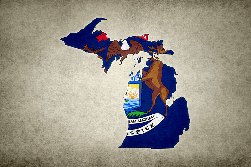 Grunge map of the state of Michigan (USA) with its flag printed within its border on an old paper.