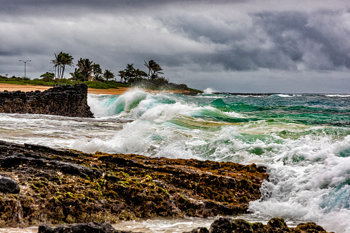 Large waves crashing along the coastline of Oahu as a storm begins to roll in.