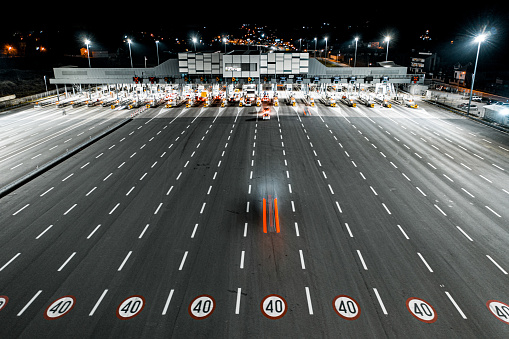 Pay toll station with only few vehicles on motorway see at night from a drone point of view.