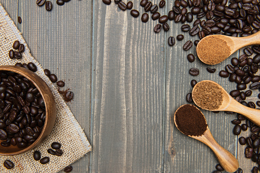 Direct above view of roasted coffee beans and  coffee types in spoons  on wood.