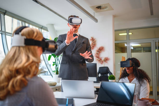 istock Businessman with Virtual Reality Simulator Standing and Explaining About Project to Coworkers 1301284828