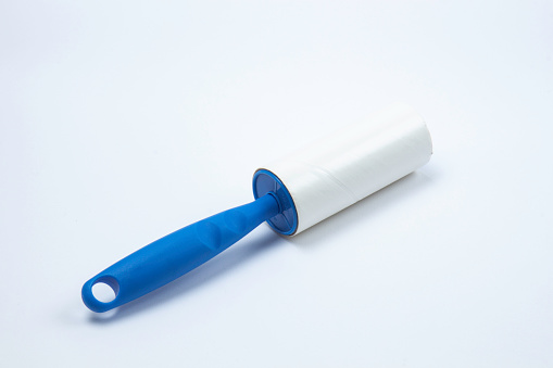 Clothes lint roller with blue handle on pure white background.