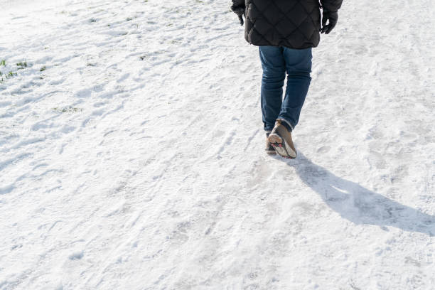 istock Man walking on compacted snow wearing anti slip rubber boot covers, with stud spikes for grip 1301286045
