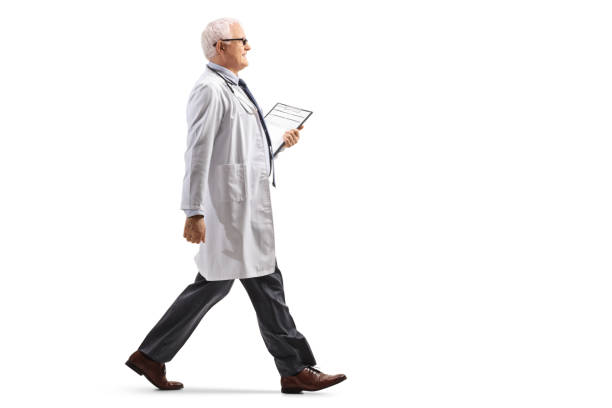 full length profile shot of a mature doctor walking - médico geral imagens e fotografias de stock