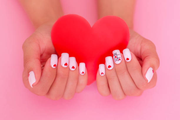 istock Female hands with white manicure, hearts design 1301287494