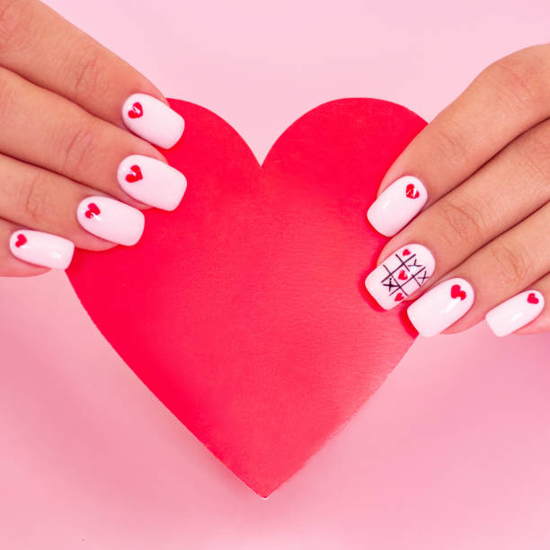 istock Female hands with white manicure, hearts design 1301287530