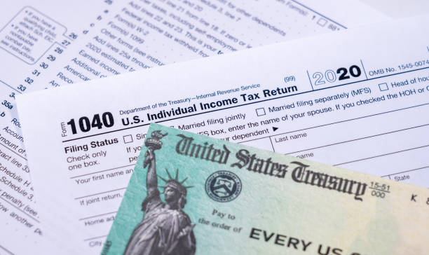 istock US Treasury check for stimulus in 2020 against a USA Form 1040 1301289633