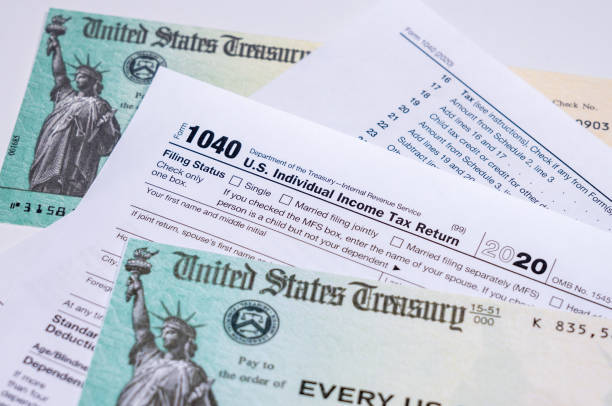 us treasury check for stimulus in 2020 against a usa form 1040 - tax form treasury check tax imagens e fotografias de stock