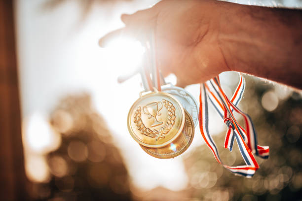 sosteniendo las medallas para la victoria - medallista fotografías e imágenes de stock