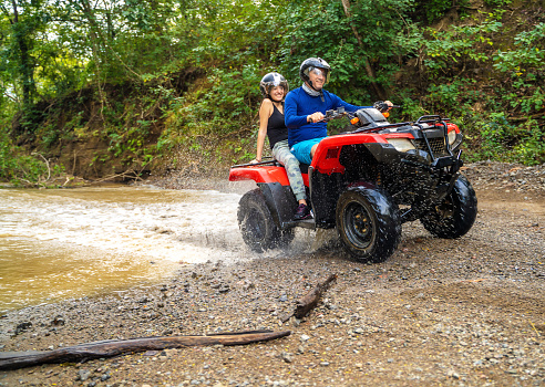 Dad and daughter crossing a small creek on 4x4 bike in Costa Rica