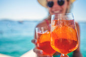 Couple toasting with a spritz cocktail on a deck beside the ocean.