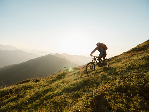 Shot of a male mountain biker enjoying a ride in the mountain at sunset.