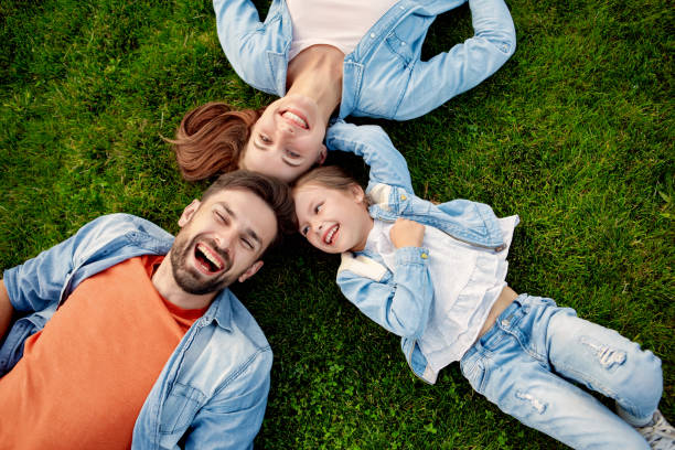 Happy family laughing, lying on green grass stock photo